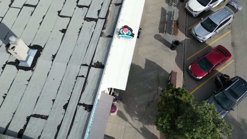 An ice cream shop in Cochrane from directly above, the queue on the pavement and the roofline.